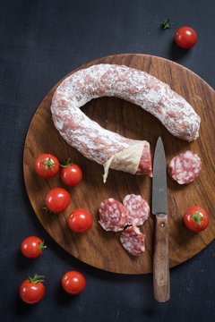 Overhead view of french salami and cherry tomatoes on cutting board