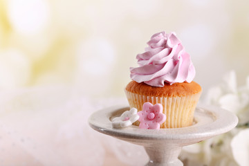 Tasty cupcake on stand, on light background