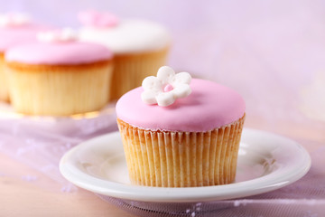 Tasty cupcake on saucer, on light background