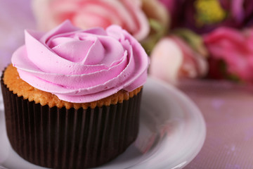 Tasty cupcake on saucer, on light background