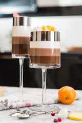 Layered chocolate desserts in glasses. Slices of mandarine on a top of sweet. Selective focus