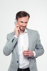 Businessman holding cup with coffee and talking on the phone