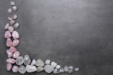 Frame of rock crystal and pink quartz on grey background, copy space