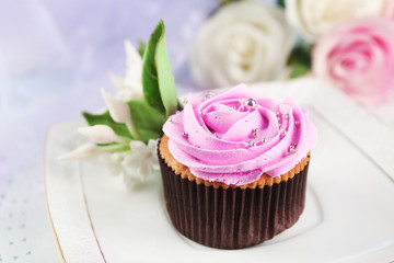 Tasty cupcake on plate, on light background