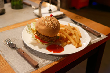 Hamburger and french fries on a plate with tomato sauce in a restaurant