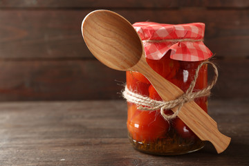 Jar of canned tomatoes on wooden background