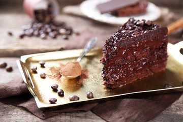 Chocolate cake with chocolate cream on tray, on wooden background