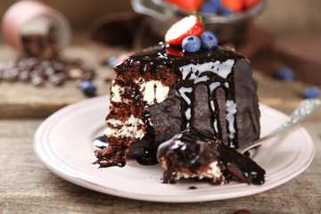 Chocolate cake with cream and fresh berries on plate, on wooden background