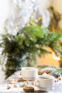 Coffee, tangerines, cookies and nuts in Christmas decor with Christmas tree, nuts and apples on colorful background bokeh