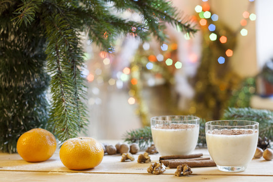 Vanilla panna cotta with chocolate,  tangerines, cones, cinnamon and nuts in Christmas decor with Christmas tree on colorful background bokeh