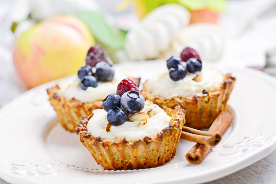 Pastry Tartlets (small tarts) with cream and berries on white plate, close up
