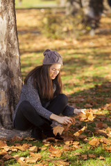 Woman drop up leaves in autumn park
