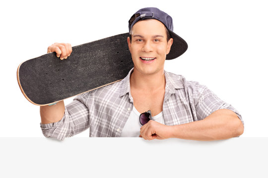 Cheerful skater posing behind a billboard