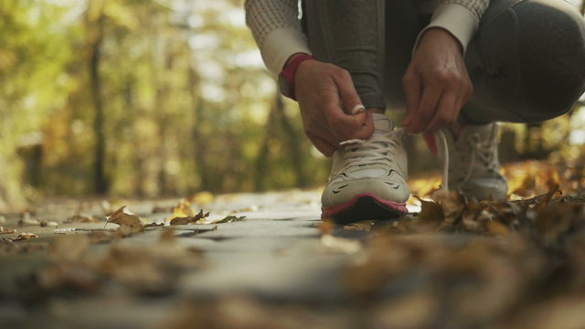 Young sporty woman preparing to run in a beautiful autumn forest, wellness concept.