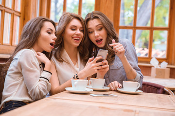 Cheerful three women using smartphone
