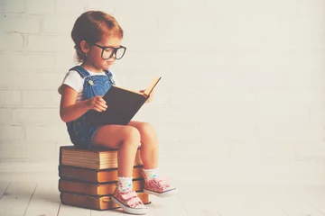 Acrylic prints Daycare child little girl with glasses reading a books
