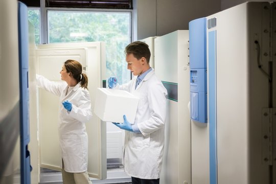 Two scientists using large fridge unit