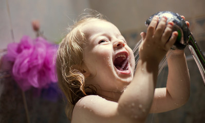 Little girl is playing with a shower