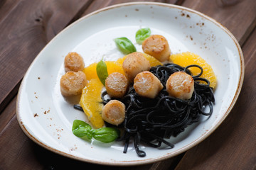 Sea scallops with squid ink colored tagliatelle and orange filet