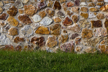 orange white brown big stone wall with green grass