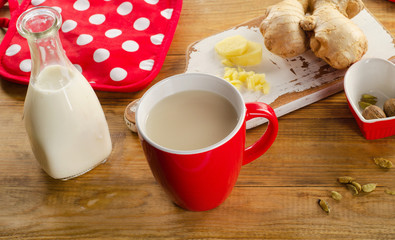 Ginger tea with milk in a cup on a wooden background.