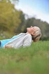 Senior woman in fitness outfit relaxing in park