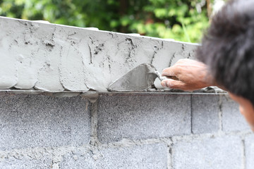 Asian boy hand using trowel with wet concrete wall