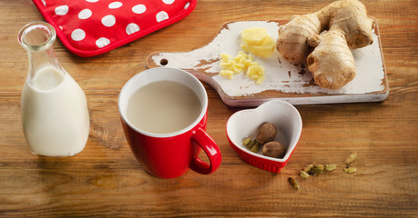 Ginger tea with milk in a cup on  wooden table.