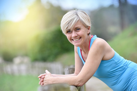 Portrait of athletic senior woman leaning on fence