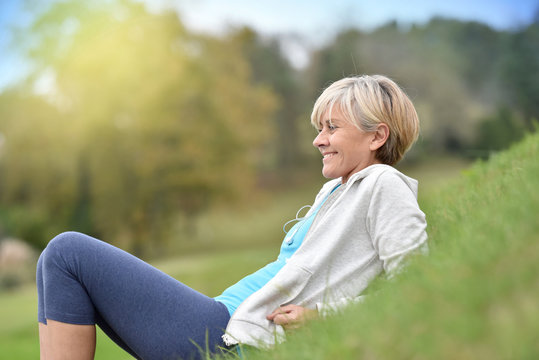 Senior woman in fitness outfit relaxing in park