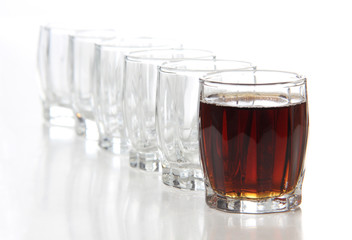 Glass cups with whiskey on white background