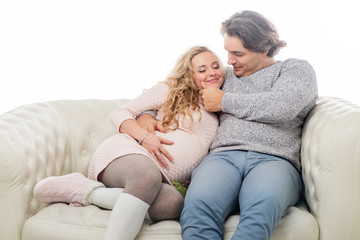 Fototapeta premium Pregnant fasion woman in knitted sweater with husband sitting on the sofa