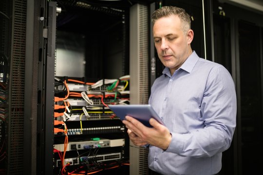Technician using tablet pc while analysing server