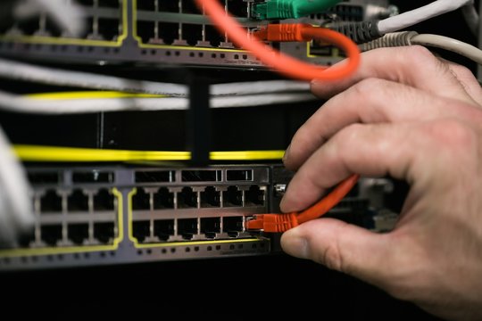 Close-up of technician inserting wire in server