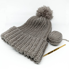 Yarn ball and finished knitted hat in gray with a golden needle