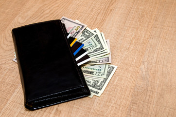 Black Wallet with credit cards and dollar banknotes over table