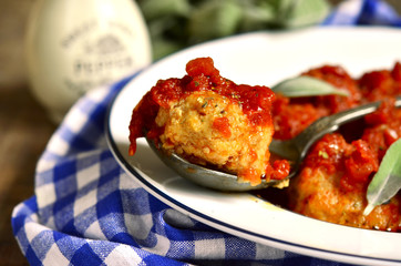 Homemade meatballs in tomato sauce with sage.