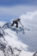 Fototapeta na wymiar Flying snowboarder on mountains. Extreme sport