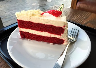Slide of red velvet cake with Christmas topping on white plate and fork