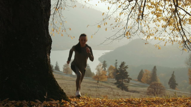 Tired female runner taking a break. Sporty women resting on running, mountain top.
