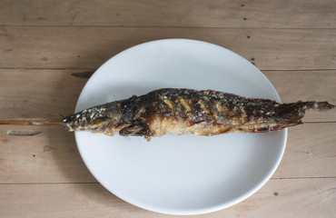 Still Life-Grilled fish on a white plate placed on a wooden table, Grilled food.