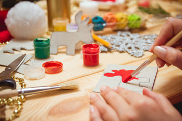 The girl at the table makes Christmas gifts. Hand made