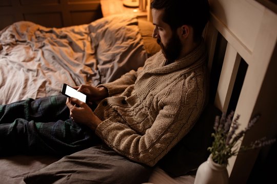 Hipster using phone in bed