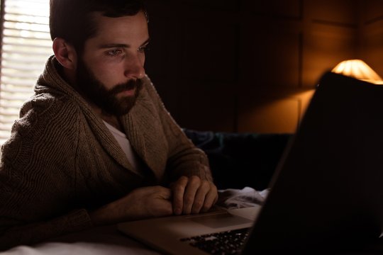 Handsome hipster using laptop in bedroom