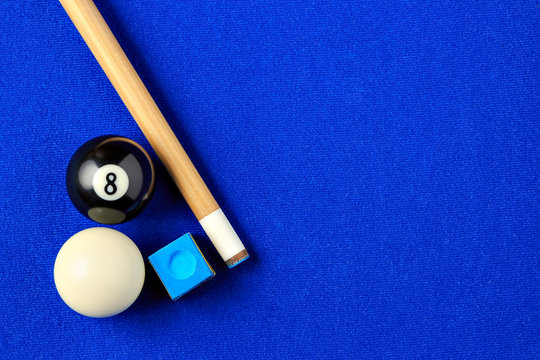 Billiard balls, cue and chalk in a blue pool table.