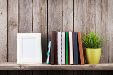 Wooden shelf with photo frames, books and plant