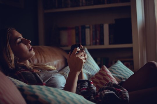 Pretty woman playing video games on sofa