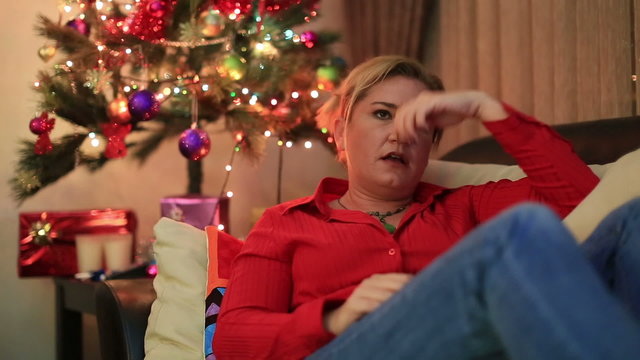 Depressive woman lying on a sofa in living room with christmas decorating