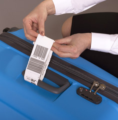 Airline check in luggage tag being attached to a suitcase