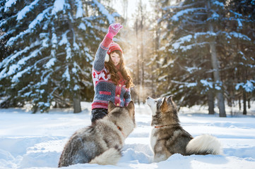 Young girl playing with the dog malamute in the winter